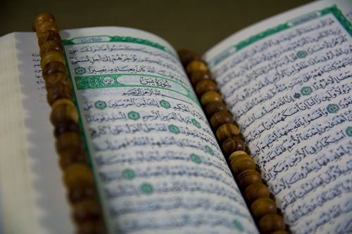 Photograph of a printed Mushaf with wooden tasbih beads on top
